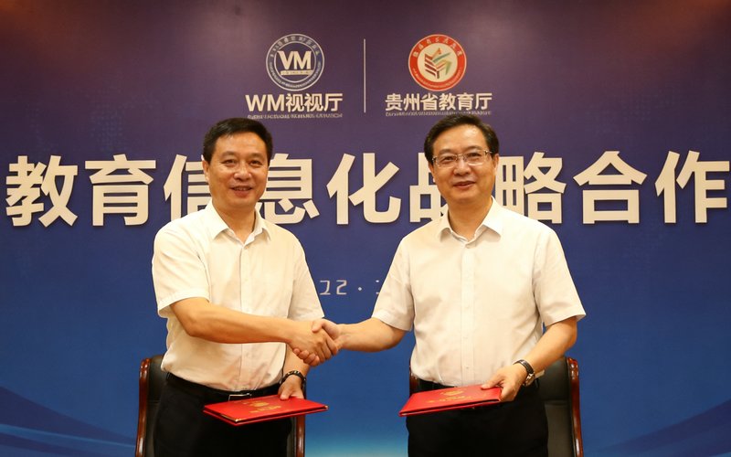 WM视讯厅与贵州省教育厅战略合作签约仪式现场，双方代表在签约台前握手并交换合作协议文本，背景板上印有双方logo和'教育信息化战略合作'字样